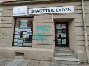 Schaufenster vom Stadtteilladen in Dresden-Johannstadt. Im Fenster sind einige Werbeplakate für Veranstaltungen zu sehen.