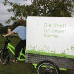 Fahrrad mit Anhänger, auf dem steht: Die Stadt ist unser Garten