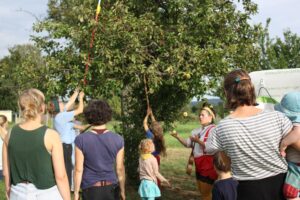 Menschen stehen vor einem Apfelbaum und ein Clown jongliert mit Äpfeln