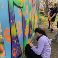 Schüler*innen bei der Gestaltung eines Mauerstücks im Johanngarten mit Street-Art