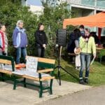 Erzählbank mit Arbeitsgruppe zur Vorbereitung im Hintergrund ein Pavillion mit zwei Musikern