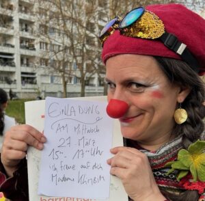 schelmiges Gesicht der Clownin mit handgeschriebener Einladung zum 27.3.15 Uhr