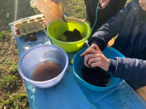 Kinderhände kneten Erde auf einem Tisch mit drei Schüsseln