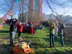 Kinder stehen mit einem Clown im Kreis auf einer Wiese und strecken die Arme nach oben