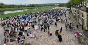 viele Menschen in Festkleidung stehen in Gruppen an der Elbe