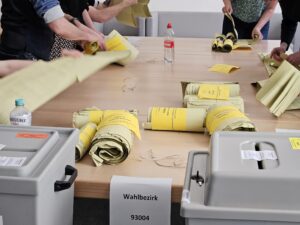 An einem Tisch werden Stimmzettel nach einer erfolgten Wahl ausgezählt.