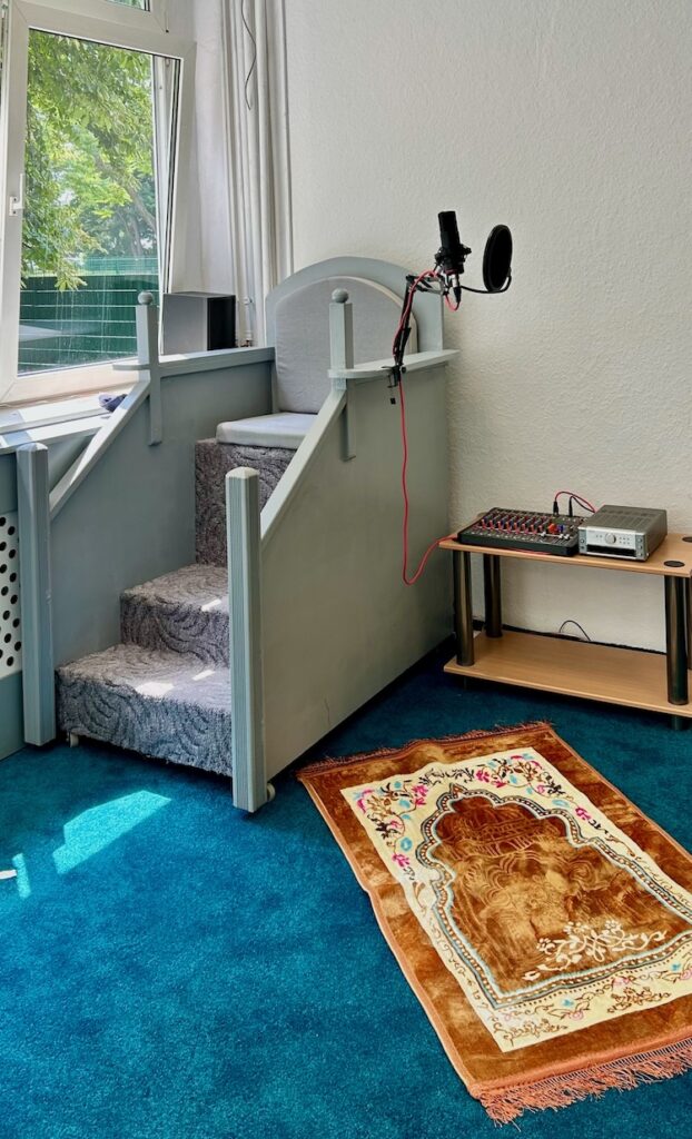 Islamischer Gebetsstuhl vor dem Fenster auf blauem Teppich