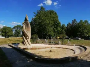 Ein Bild, dass enthält blauer Himmel, Baum, Wiese, Brunnen mit Wasserfontänen.