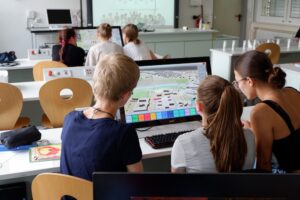 Kinder sitzen in einem Klassenraum vor Bildschirmen