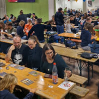 Zahlreiche Teilnehmer sitzen an Tischen und spielen Brettspiele
