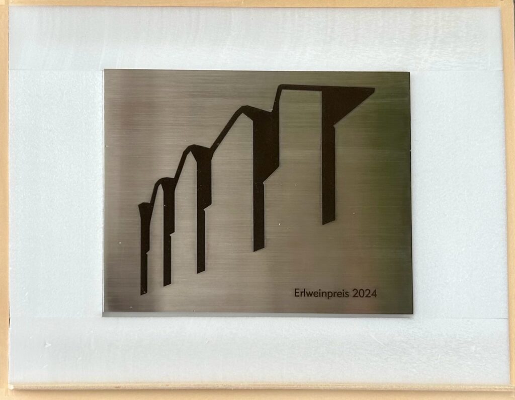 eine Metallplakette mit vier symbolischen Mauerbögen