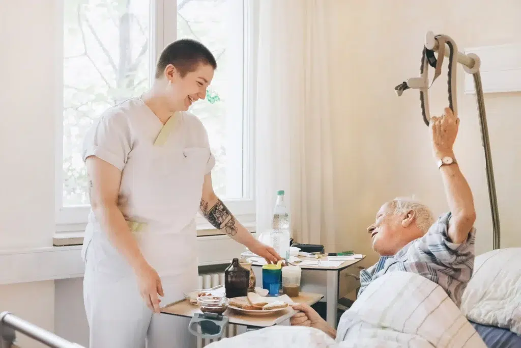 Pflegerin steht am Krankenbett und betreut einen Patienten.
