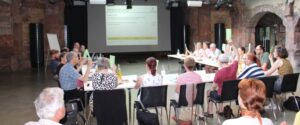 Stadtteilbeiräte halten Stimmkarten in die Höhe bei der 6. Sitzung des Dritten Stadtteilbeirats