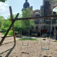 Zwei Schaukeln auf dem Spielplatz an der Kirche.