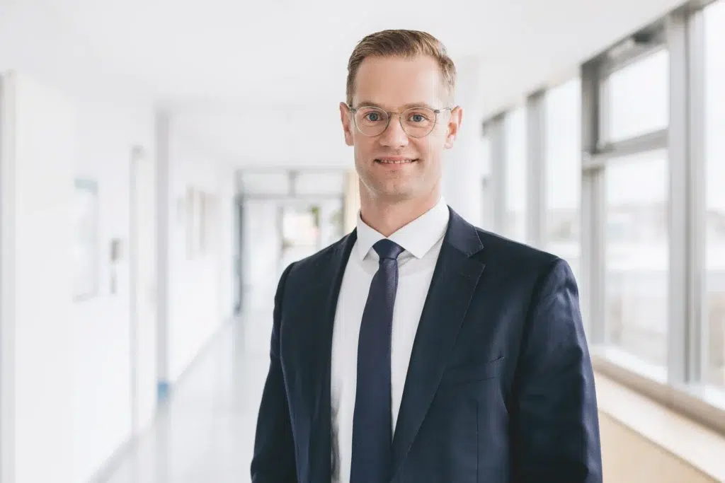 Ein Mann mittleren Alters, mit Brille und im Anzug.